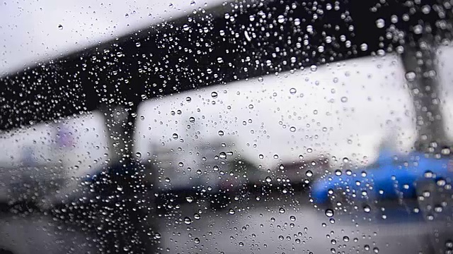 近距离拍摄雨滴在汽车车窗玻璃和模糊的交通环境下，阴雨昏暗的背景视频素材