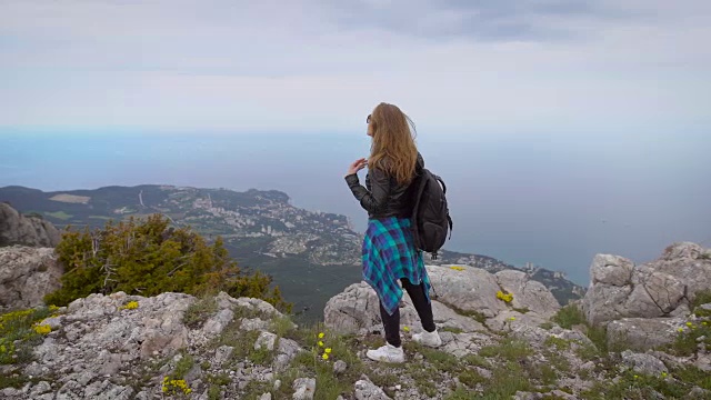 女旅行者看着悬崖的边缘上的海湾山的背景视频素材