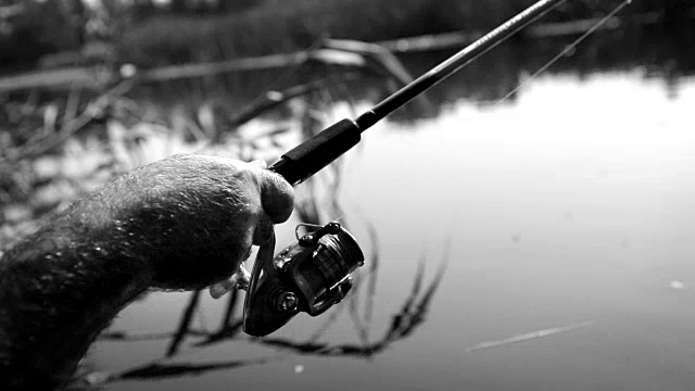 黑色和白色的视频，一个勺子上的线圈在钓鱼期间由一个渔夫旋转视频素材