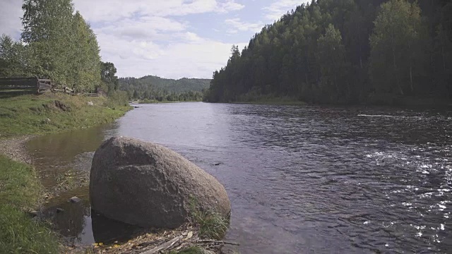 巨大的石头栖息在河岸附近，河对岸是黑森林视频素材