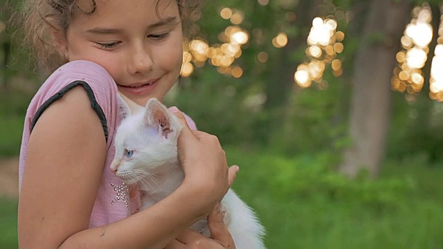 十几岁的女孩棕发抱着小猫在她的猫怀里爱户外视频素材