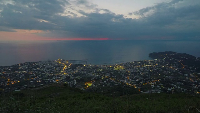 临近海边的度假小镇，夜晚城市灯光缓缓流逝，从山顶俯瞰视频素材