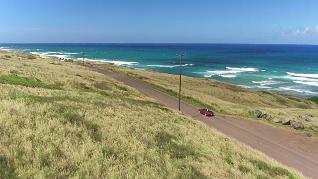 航拍:红色敞篷车在夏威夷岛海岸公路上行驶视频素材