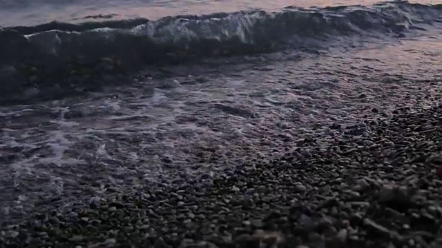 随着太阳的落山，海浪慢慢地冲上海滩，慢慢地退去。视频素材