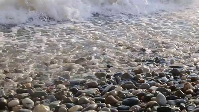 随着太阳的落山，海浪慢慢地冲上海滩，慢慢地退去。视频素材