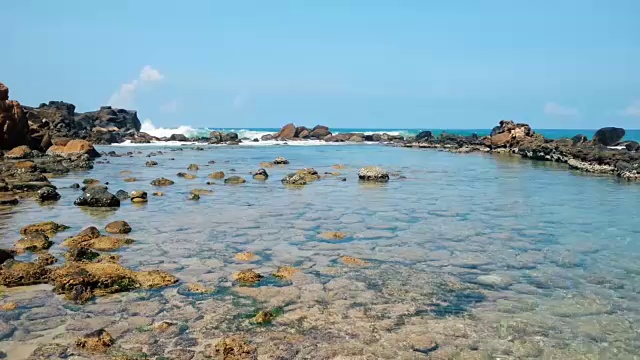 安静的浅水里有珊瑚，海浪拍打着岩石屏障视频素材