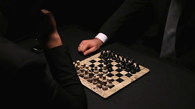 两名选手穿着西装坐在一间黑暗的房间里下棋视频素材