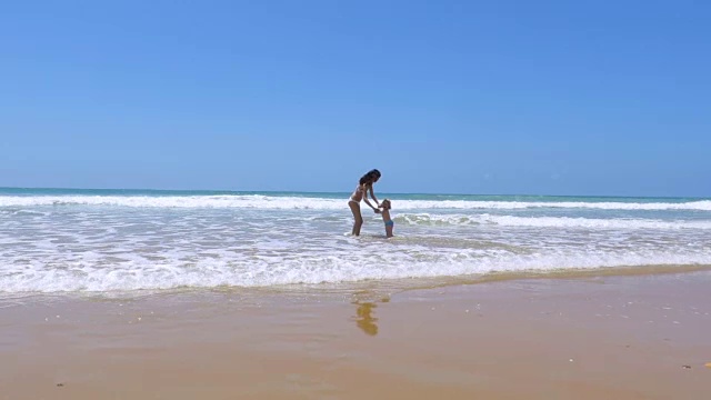 宝宝在海滩上蹦蹦跳跳地向妈妈跑去视频素材