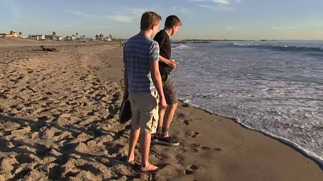 十几岁的男孩在海滩和岩石上散步视频素材