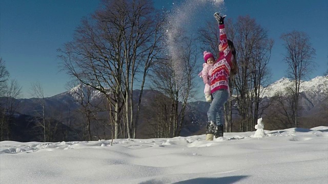 快乐的年轻妈妈在雪中和婴儿玩。慢动作视频素材