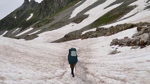 一名背着徒步背包的游客从高加索地区的高雪山上下来视频素材