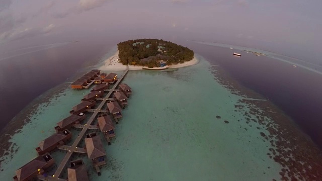 鸟瞰海上日落和豪华的水上别墅在热带岛屿度假，马尔代夫。视频素材