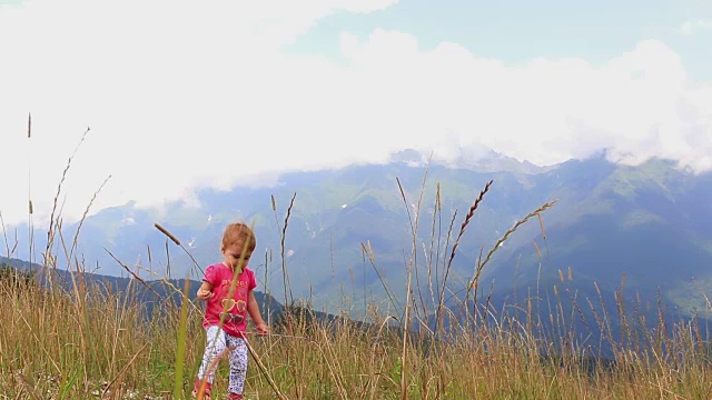 在一个炎热的夏天，一个小孩子走过高山上的草丛。全高清。1920 x1080视频下载