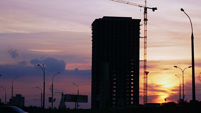 夕阳下的建筑工程剪影。城市景观与汽车和建筑工地视频素材