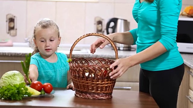 女孩帮助妈妈从篮子里拔菜视频素材