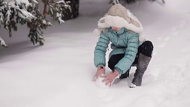 小女孩在冬季公园堆雪人。雪花从天上飘落。视频素材