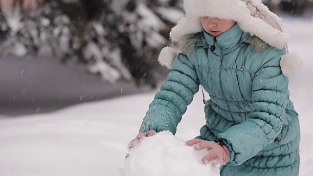 女孩冬天在雪地里堆雪人。视频素材