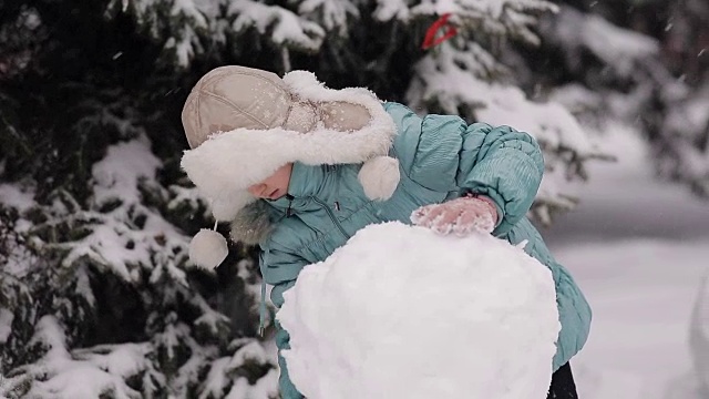 女孩冬天在雪地里堆雪人。视频素材