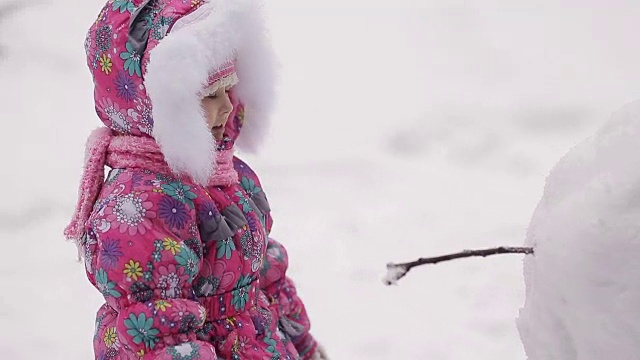 女孩冬天在雪地里堆雪人。视频素材