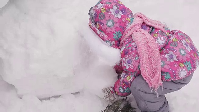 女孩冬天在雪地里堆雪人。视频素材