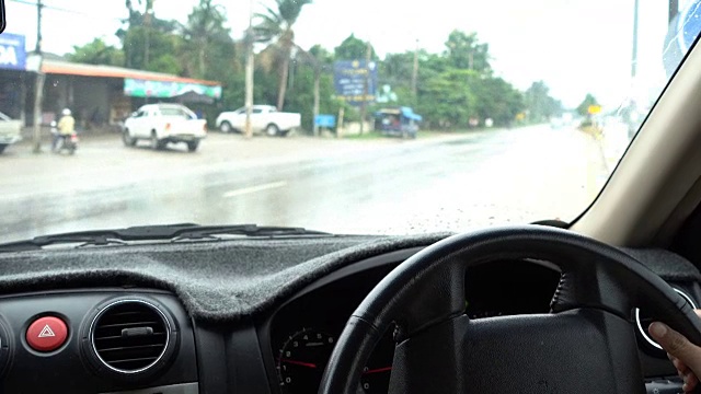 在雨天开车穿过城市的女人的车里看视频素材