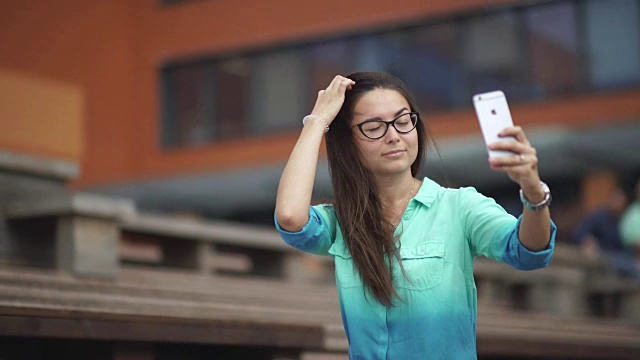 年轻漂亮的女孩在用手机自拍视频素材