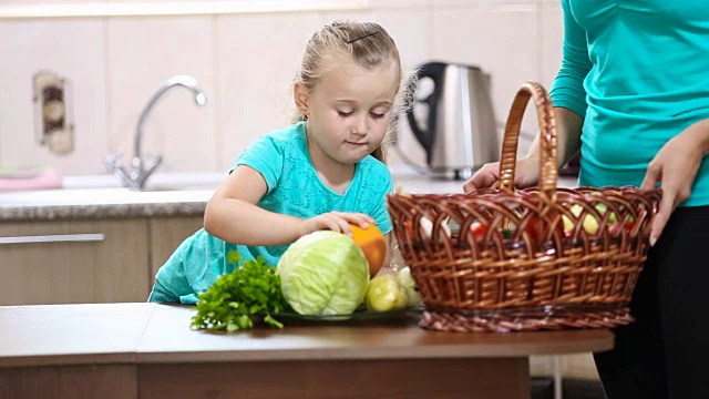 女孩帮助妈妈从篮子里拔菜视频素材