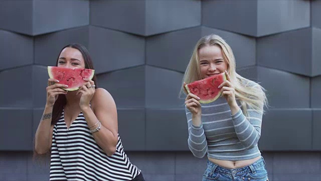 两个小女孩在街上吃西瓜的照片视频素材