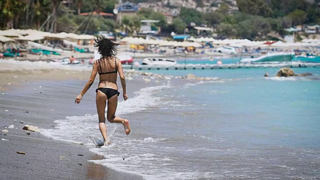 一个年轻漂亮的女人在塞浦路斯的海滩上跑步视频素材