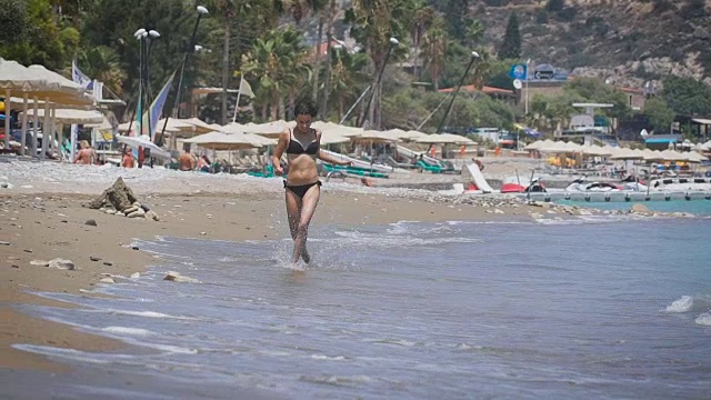 一个年轻漂亮的女人在塞浦路斯的海滩上跑步视频素材