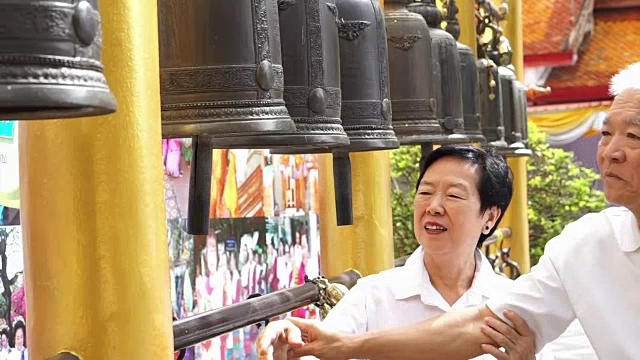 亚洲老夫妇在佛寺里敲钟，相信会带来好运视频素材