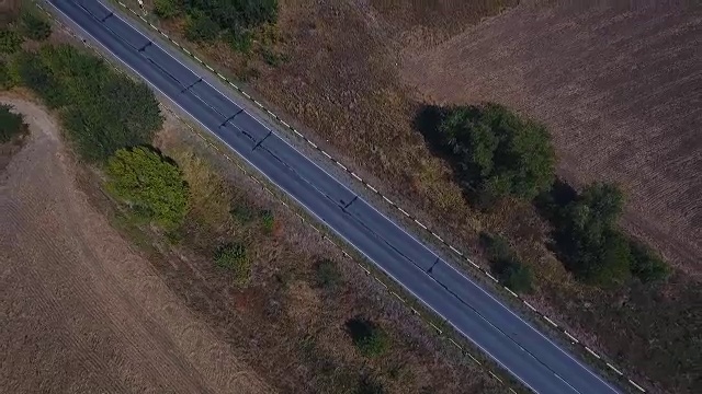 鸟瞰图的村庄道路和收获的田地。视频素材