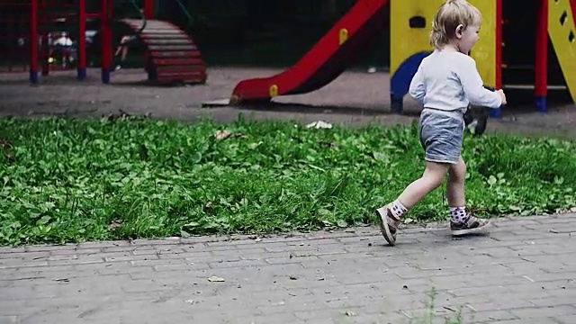 母亲抱着孩子，儿子在公园里喂鸽子。男孩跑，鸟儿飞走了视频素材