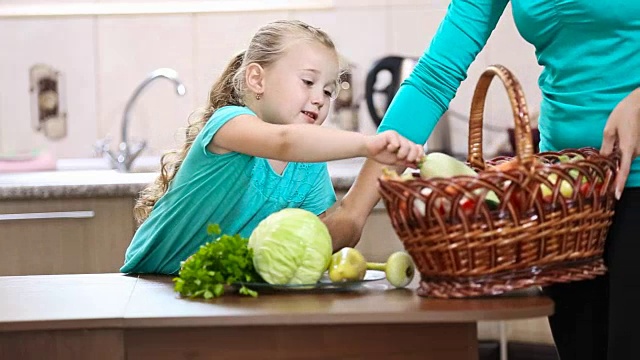 女孩帮助妈妈从篮子里拔菜视频素材