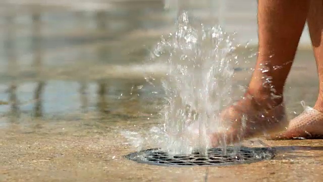 水从地下涌出。人的脚玩水。水流落到地面。特写镜头视频素材