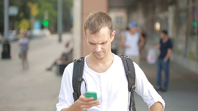 一个男人在大街上打手机。年轻人用智能手机发短信。视频素材