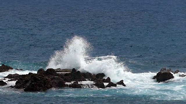 海浪冲击着熔岩岩石。两个游戏速度。缓慢的运动。视频素材