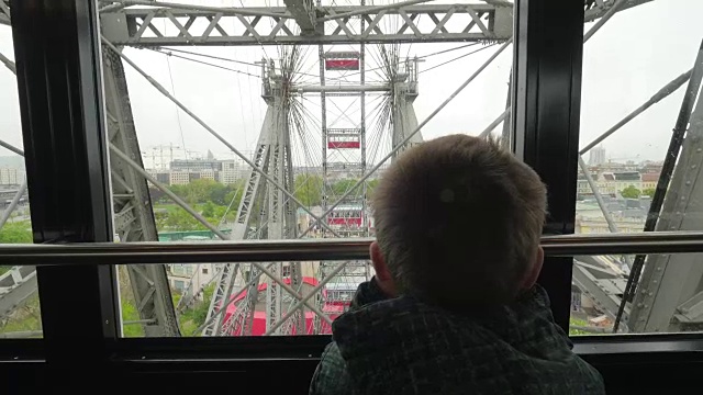 在奥地利的维也纳，小男孩从摩天轮的窗口看城市视频素材