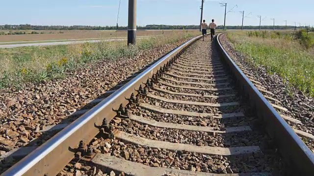 两个人在铁轨之间奔跑。短跑运动员在铁路枕木上慢跑。夏季户外运动运动员的腿部训练。积极健康的生活方式。特写镜头视频素材