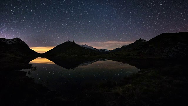 银河的旋转和雪山外的星空，映照在田园诗般的松树湖上。猎户座从左到右。时间流逝的视频。视频素材