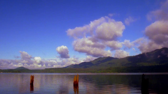 广角拍摄的时间推移云翻滚的山和湖与木杆在水中前景/奥林匹克半岛，华盛顿视频素材