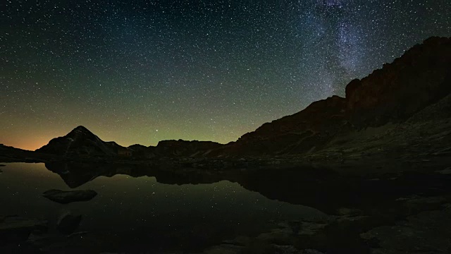 银河的旋转和雪山外的星空，映照在田园诗般的松树湖上。时间流逝的视频。视频素材