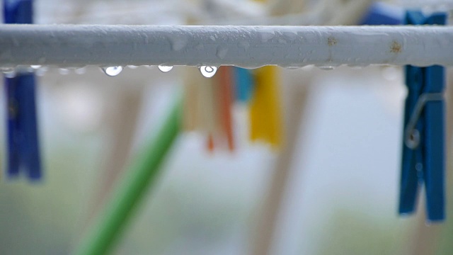 两个衣夹(黄色和橙色)在户外的雨中视频素材