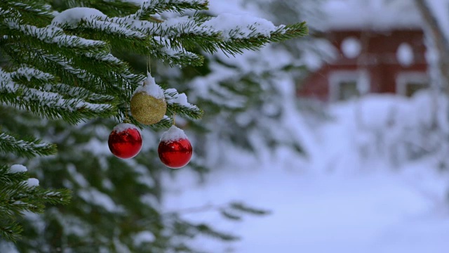 雪和圣诞球在树附近的房子。无缝循环视频素材