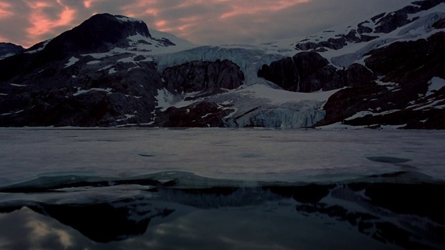 宽镜头的时间推移云在部分冻结的湖与雪山的背景在黄昏/不列颠哥伦比亚省视频素材