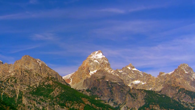 低角度的时间流逝云在蓝天上移动在崎岖的山顶/大提顿国家公园，怀俄明州视频素材