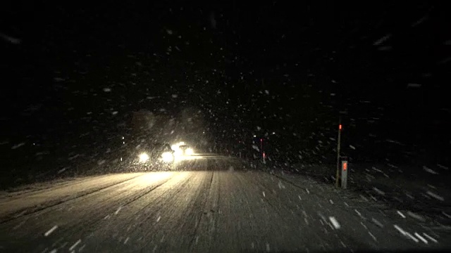 FPV(慢动作):在暴风雪的夜晚，汽车在主干道上缓慢行驶视频素材