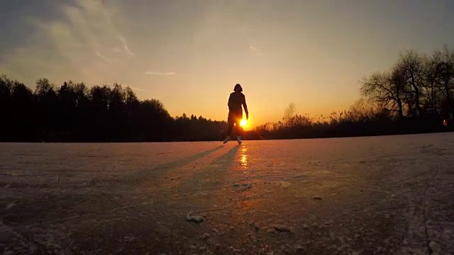 低角度:在金色的夕阳下，顽皮的年轻人在冰池上滑冰视频素材