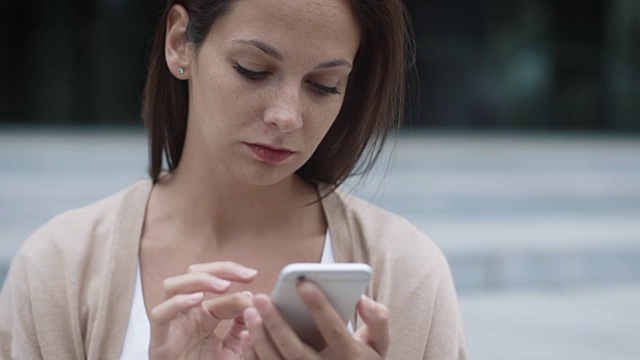 年轻迷人的女人在户外使用手机。视频素材