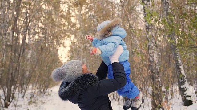 妈妈和宝宝在冬天的公园玩。妈妈把孩子吐了出来视频素材